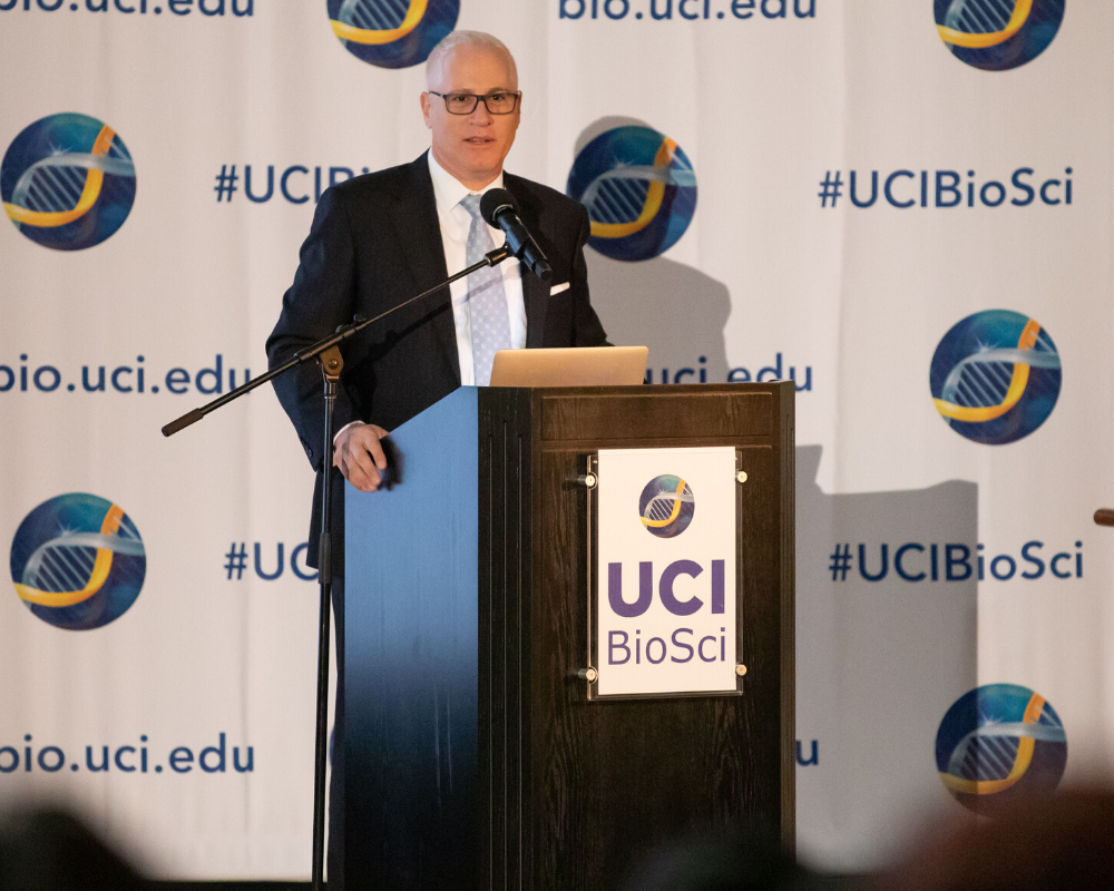 Dean LaFerla v3 Dean Laferla, PhD. speaking at a podium