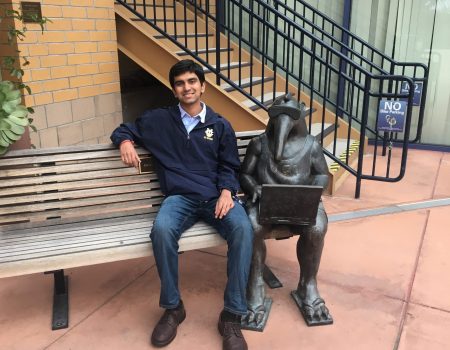 Portrait of Eashan sitting by an anteater statue on a bench