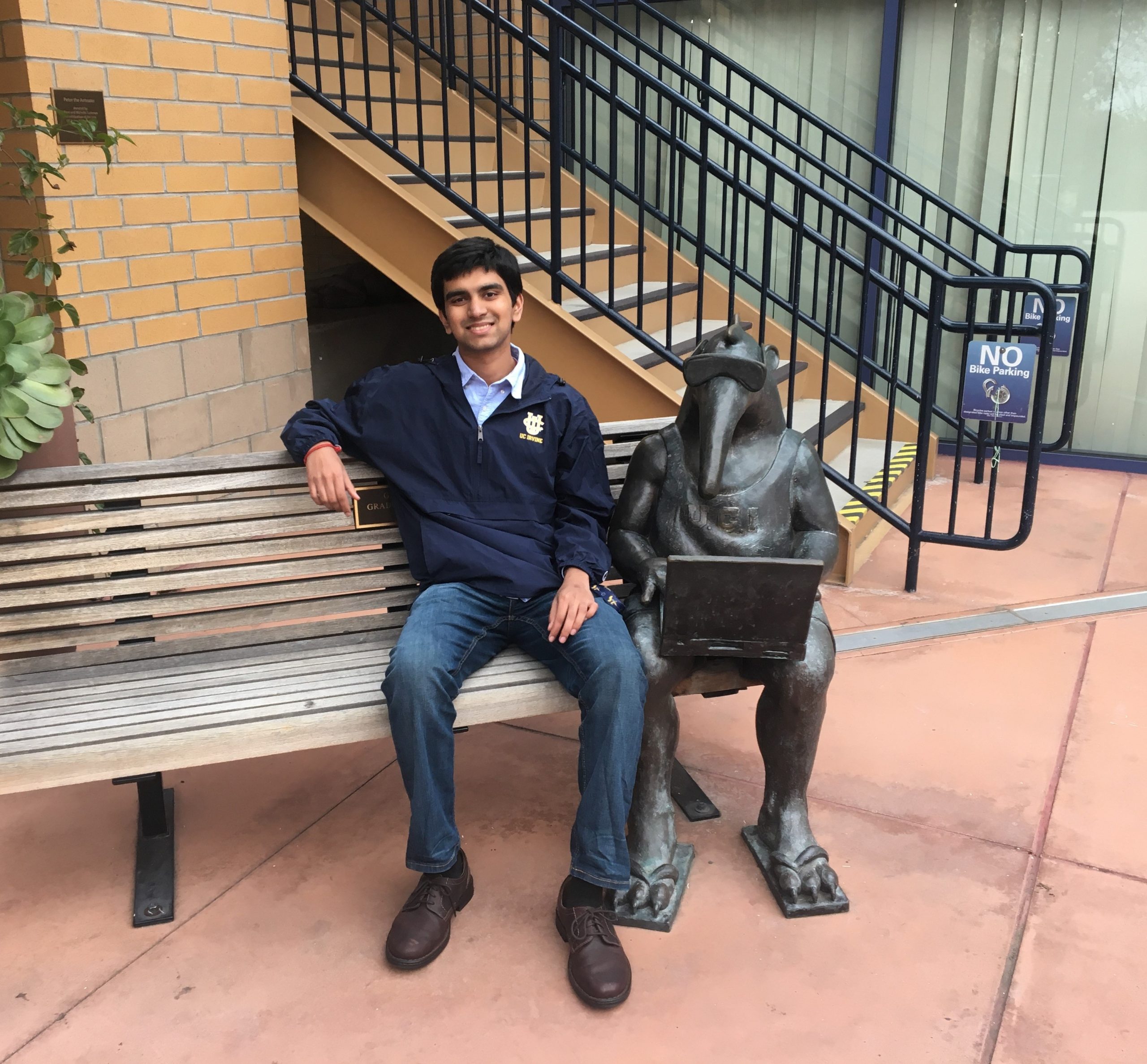 Portrait of Eashan sitting by an anteater statue on a bench