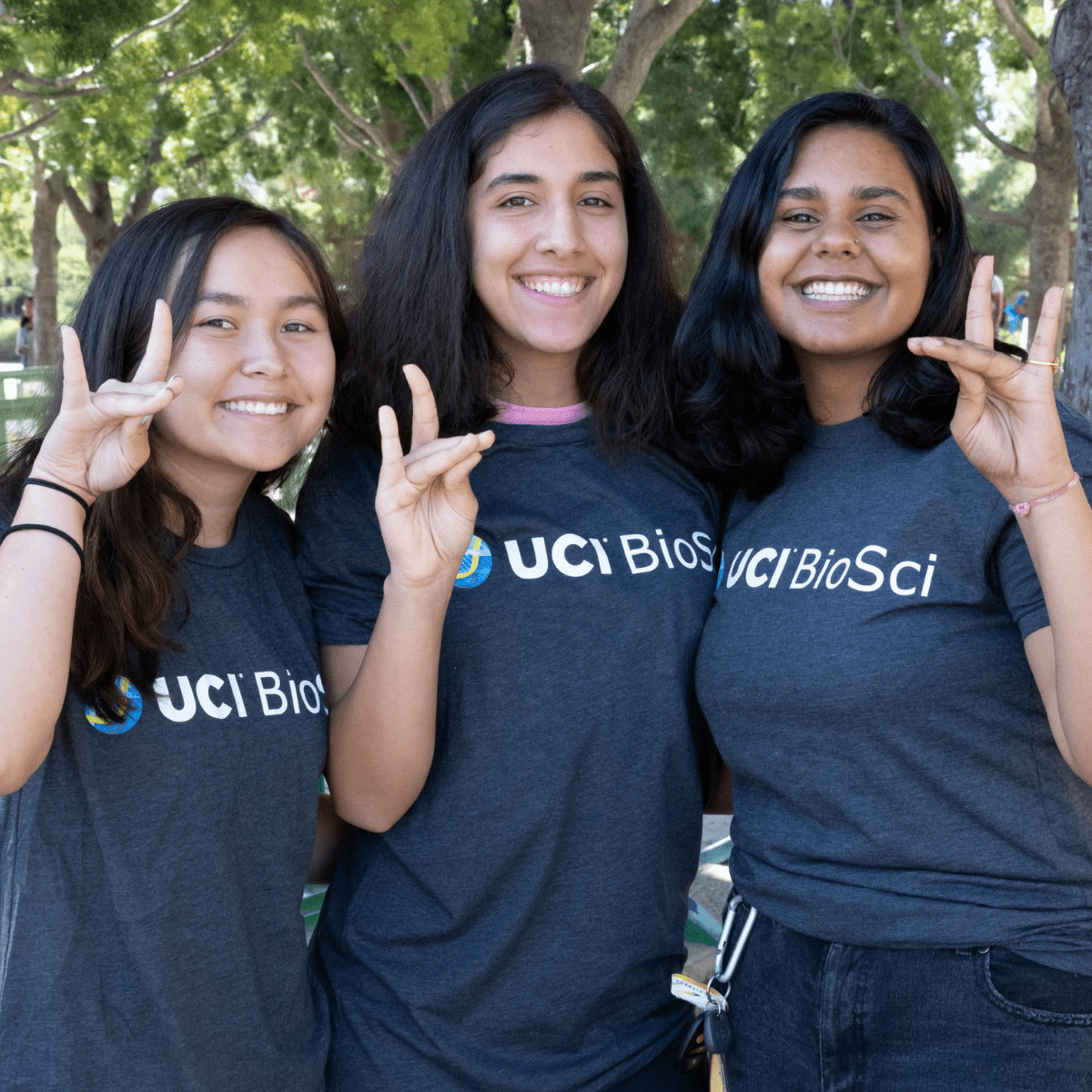 3 BioSci Students wearing a UCI BioSci tshirt while making the anteater with their hands