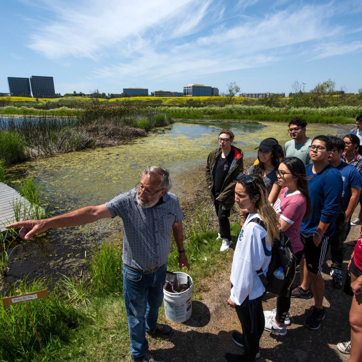 Students out in field with Professor Bowler showing them something out of the frame