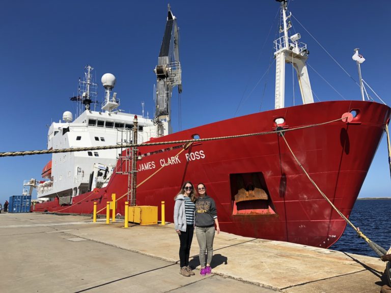 Researchers near a red ship by the ocean