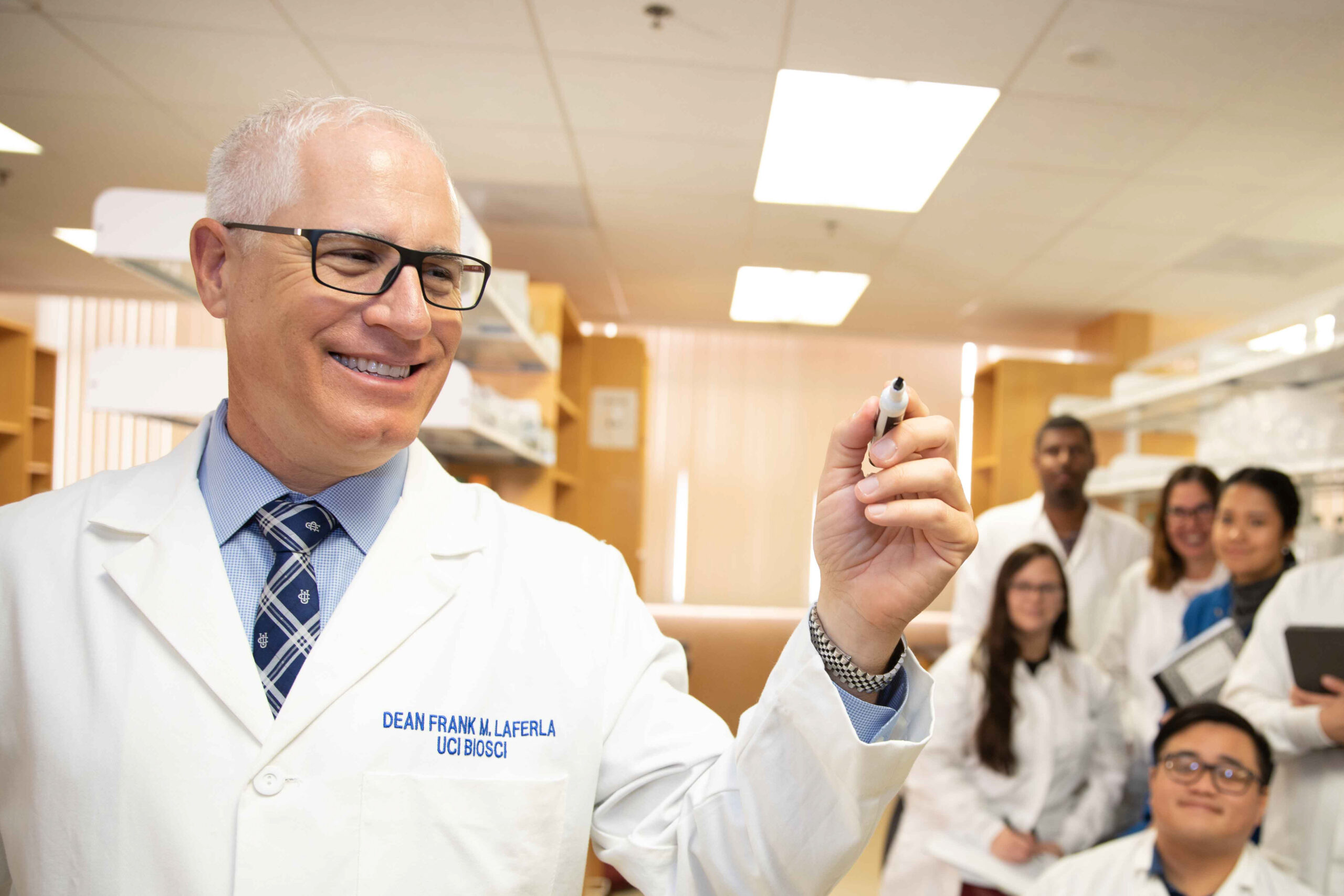 Dean Frank LaFerla in lab coat with lab staff